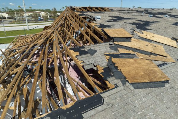 Consequences of natural disaster. Damaged house roof with missing shingles after hurricane Ian in Florida.